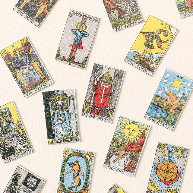 A close-up of a unique unisex tarot card necklace with a miniature card deck visible inside a geometric brass pendant.