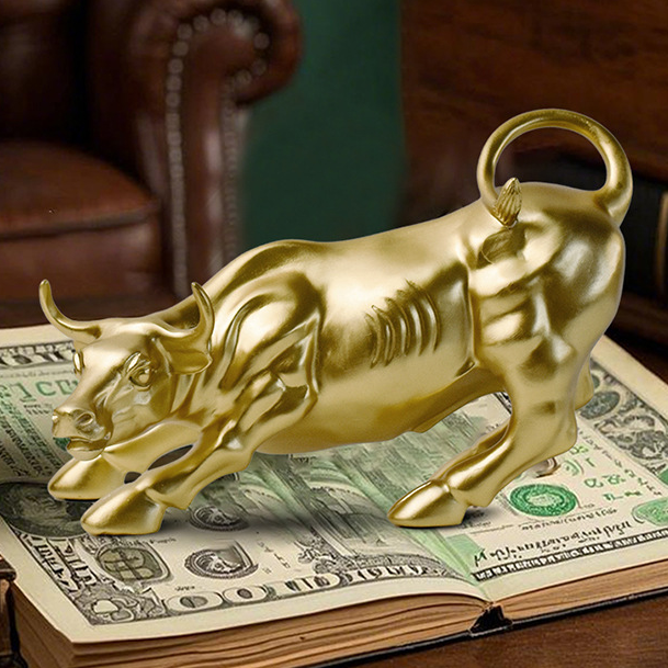 A shiny wallstreet gold bull figurine standing on an open stack of U.S.